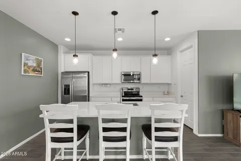 a kitchen with stainless steel appliances kitchen island granite countertop a dining table chairs and white cabinets