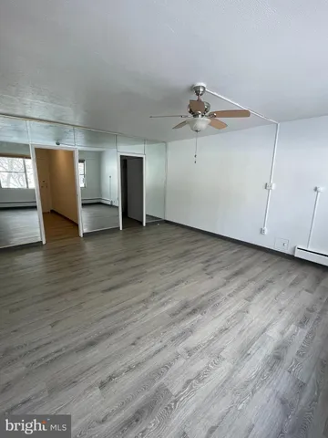 an empty room with wooden floor ceiling fan and windows