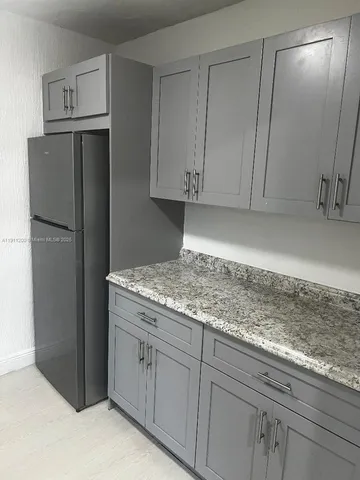 a kitchen with granite countertop cabinets and refrigerator