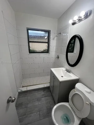 a bathroom with a toilet sink vanity granite and mirror