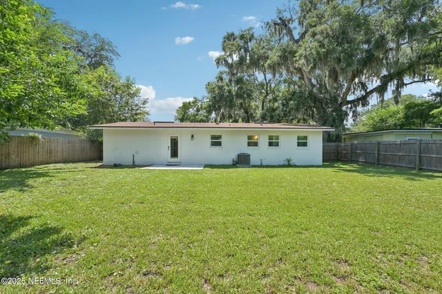 a view of a white house with a big yard and a large tree