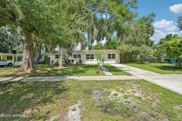a view of a house with a big yard and large trees