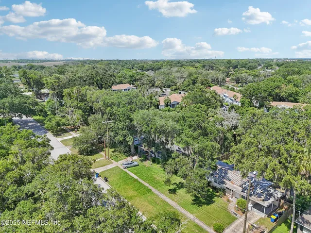 an aerial view of residential houses with outdoor space and trees