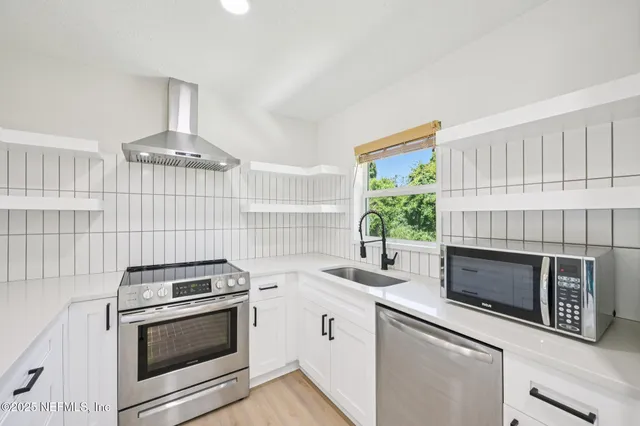 a kitchen with white cabinets stainless steel appliances and wooden floor