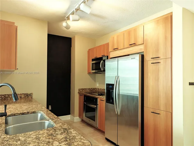 a kitchen with stainless steel appliances granite countertop a refrigerator and a sink