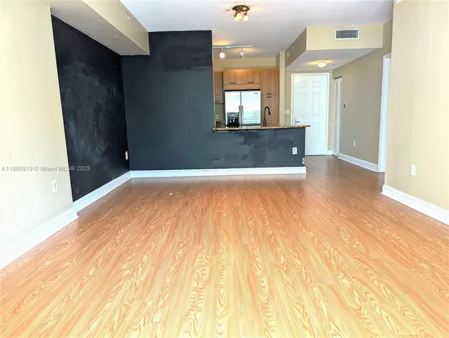 a view of a hallway with wooden floor and a large mirror