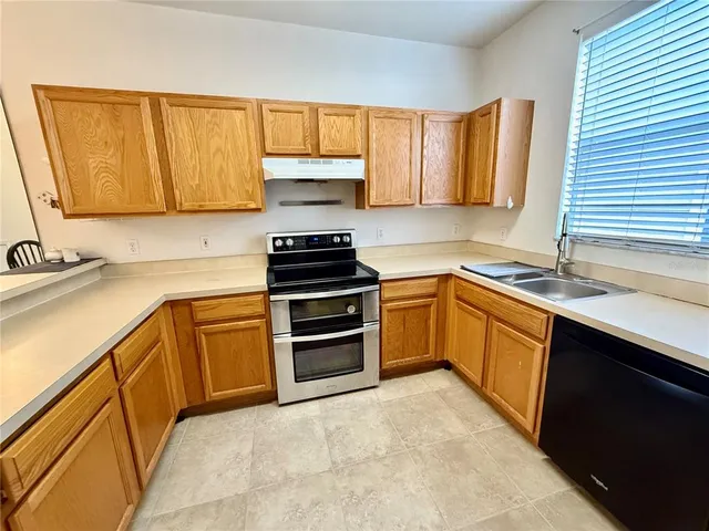 a kitchen with a sink a stove cabinets and a window