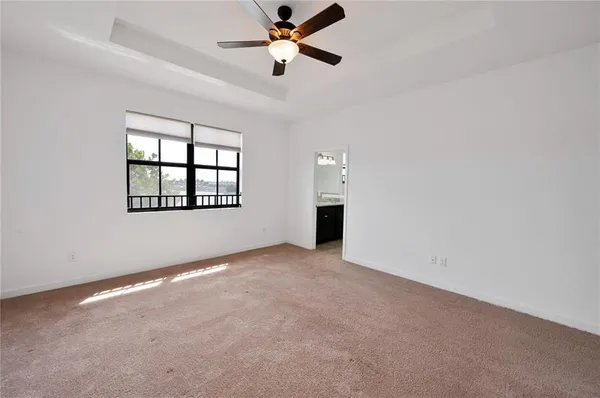 an empty room with ceiling fan and windows