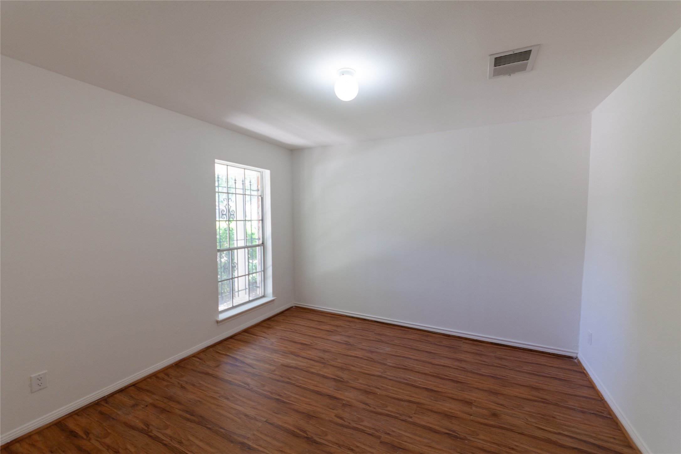 8826 Roos Road Houston, TX 77036 - Photo 18 of 42 The Bed room 2 features a bright, airy space with clean white walls and wood flooring. It has a large window that allows natural light to fill the room, creating a welcoming atmosphere. This room can be a Personal Office.