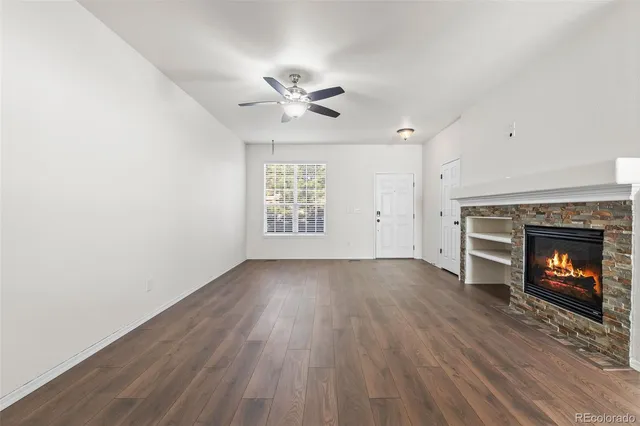 an empty room with windows fireplace and wooden floor