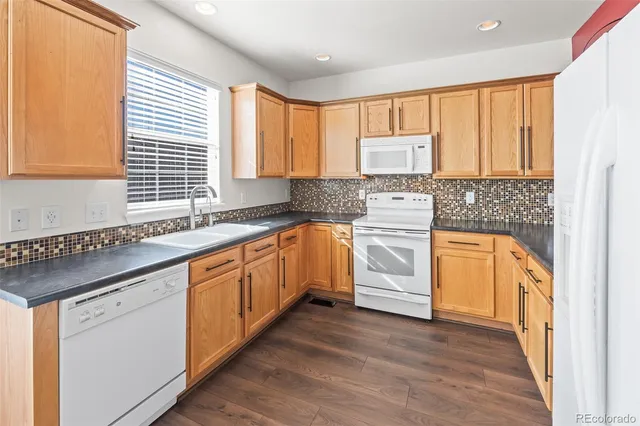 a kitchen with granite countertop wooden floors and white stainless steel appliances