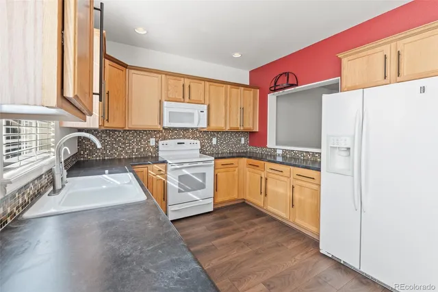 a kitchen with granite countertop a stove a sink and a refrigerator