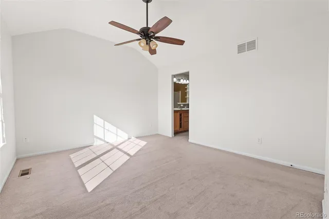 a view of an empty room and a chandelier fan