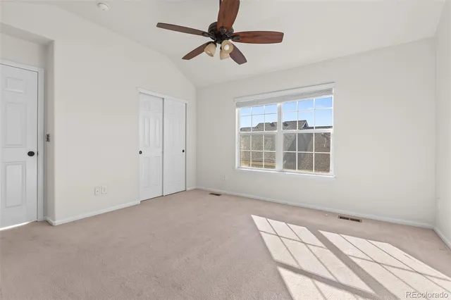 an empty room with a ceiling fan and a window