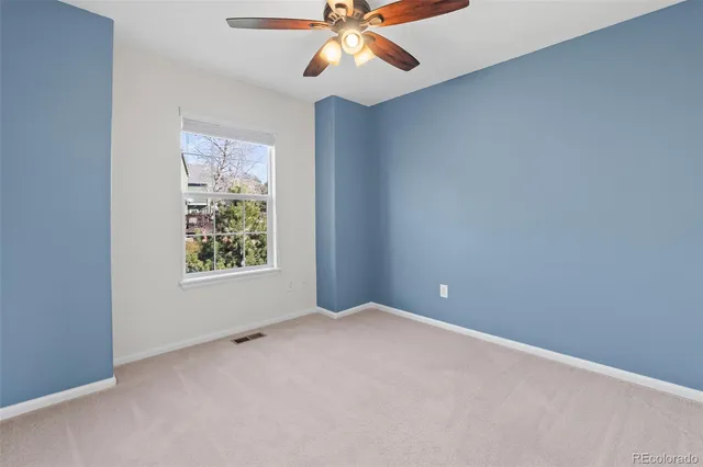 an empty room with windows and fan