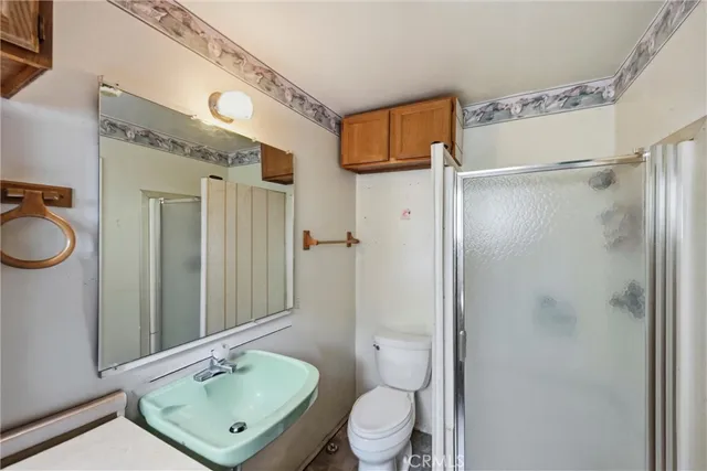 a bathroom with a sink a toilet a mirror and shower
