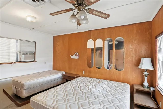 a bedroom with a bed and dresser with wooden floor