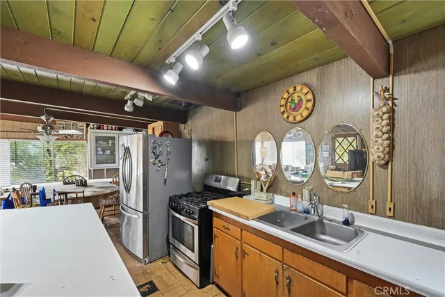 a kitchen with stainless steel appliances granite countertop a sink a stove top oven a chimney and a refrigerator