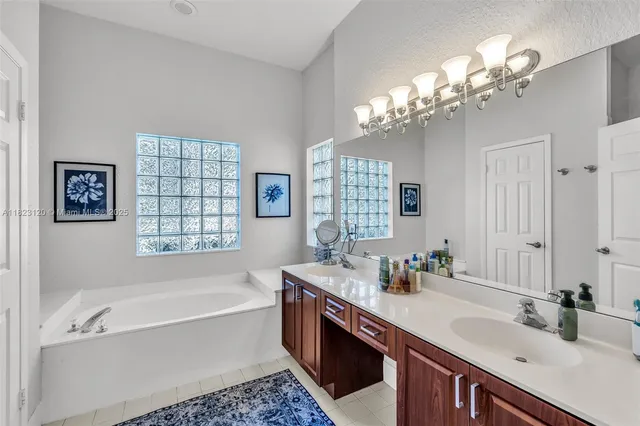 a bathroom with a tub a double vanity sink a window and a mirror