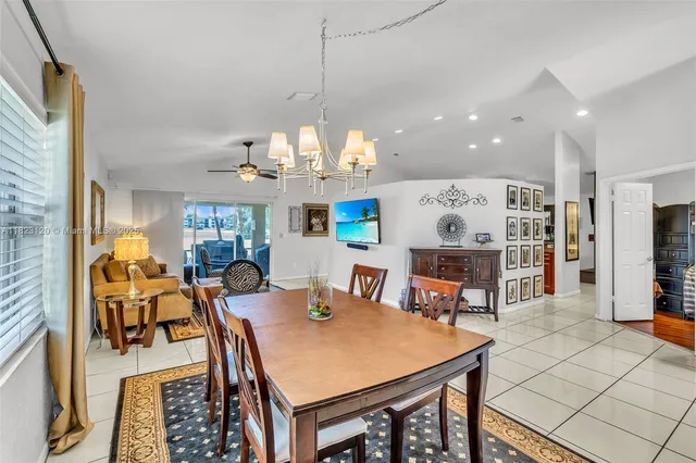a view of a dining room and livingroom with furniture a rug a kitchen appliances and a chandelier