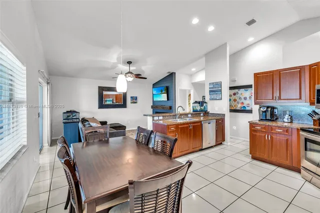 a kitchen with stainless steel appliances granite countertop a stove a sink dishwasher a dining table and chairs with wooden floor