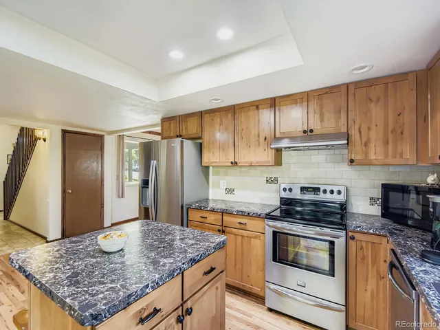 a view of kitchen island with stainless steel appliances wooden floor dining table and chairs