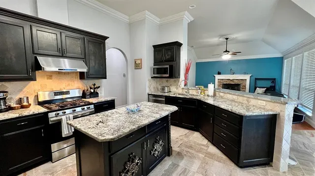 a kitchen with granite countertop kitchen island stainless steel appliances a sink stove and refrigerator