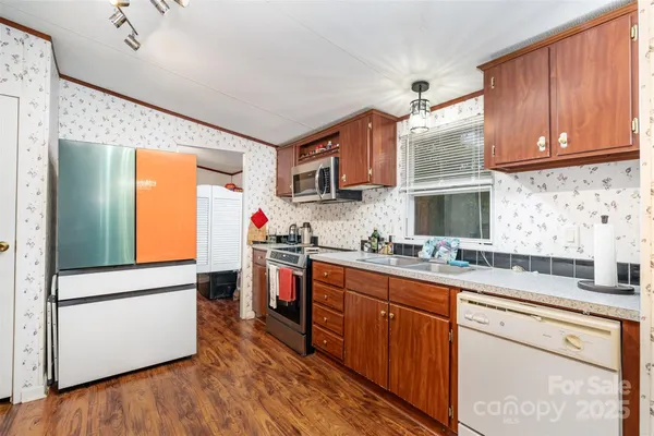 a kitchen with stainless steel appliances granite countertop a sink dishwasher stove and wooden cabinets
