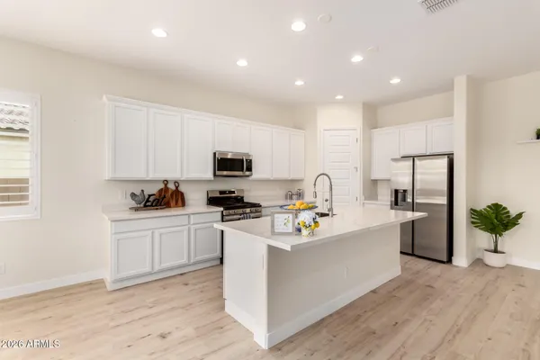 a kitchen that has a lot of white cabinets and stainless steel appliances