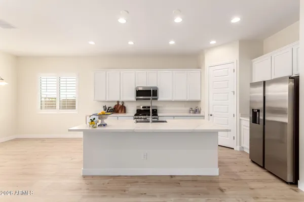 a view of a kitchen with kitchen island a sink wooden floor and stainless steel appliances