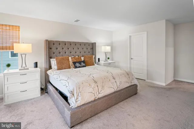 a bedroom with a bed and a lamp on dresser