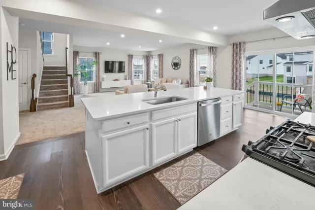 a large white kitchen with stainless steel appliances granite countertop a stove and a sink