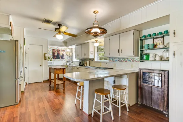 a open kitchen with granite countertop a stove a sink dishwasher and a dining table with wooden floor