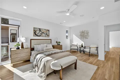 a spacious bedroom with a bed a couch and a potted plant on the dresser