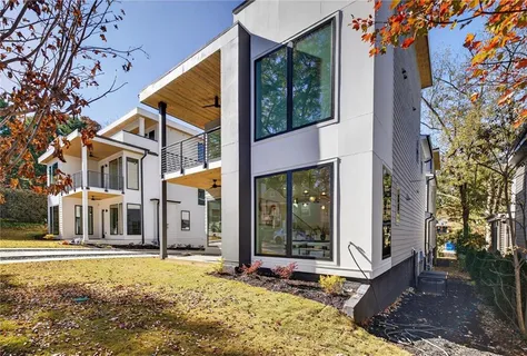 a view of a white house with a large tree in front of it