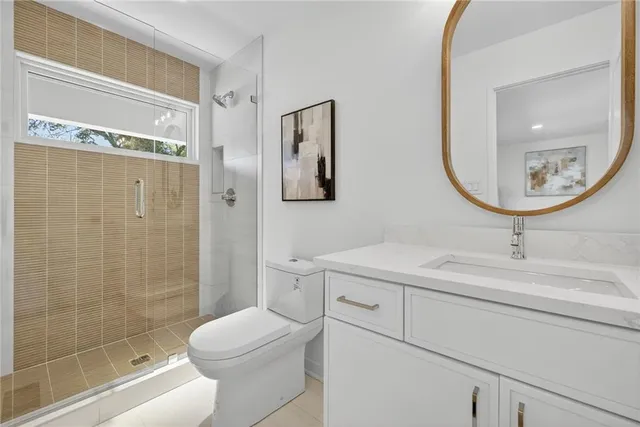 a bathroom with a toilet sink vanity granite and shower