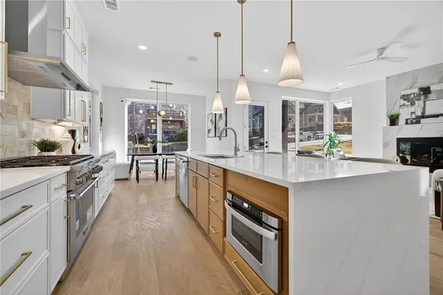 a large kitchen with stainless steel appliances a large counter top a stove a chimney a sink and a refrigerator