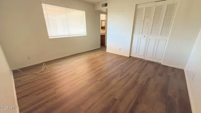 an empty room with wooden floor and windows
