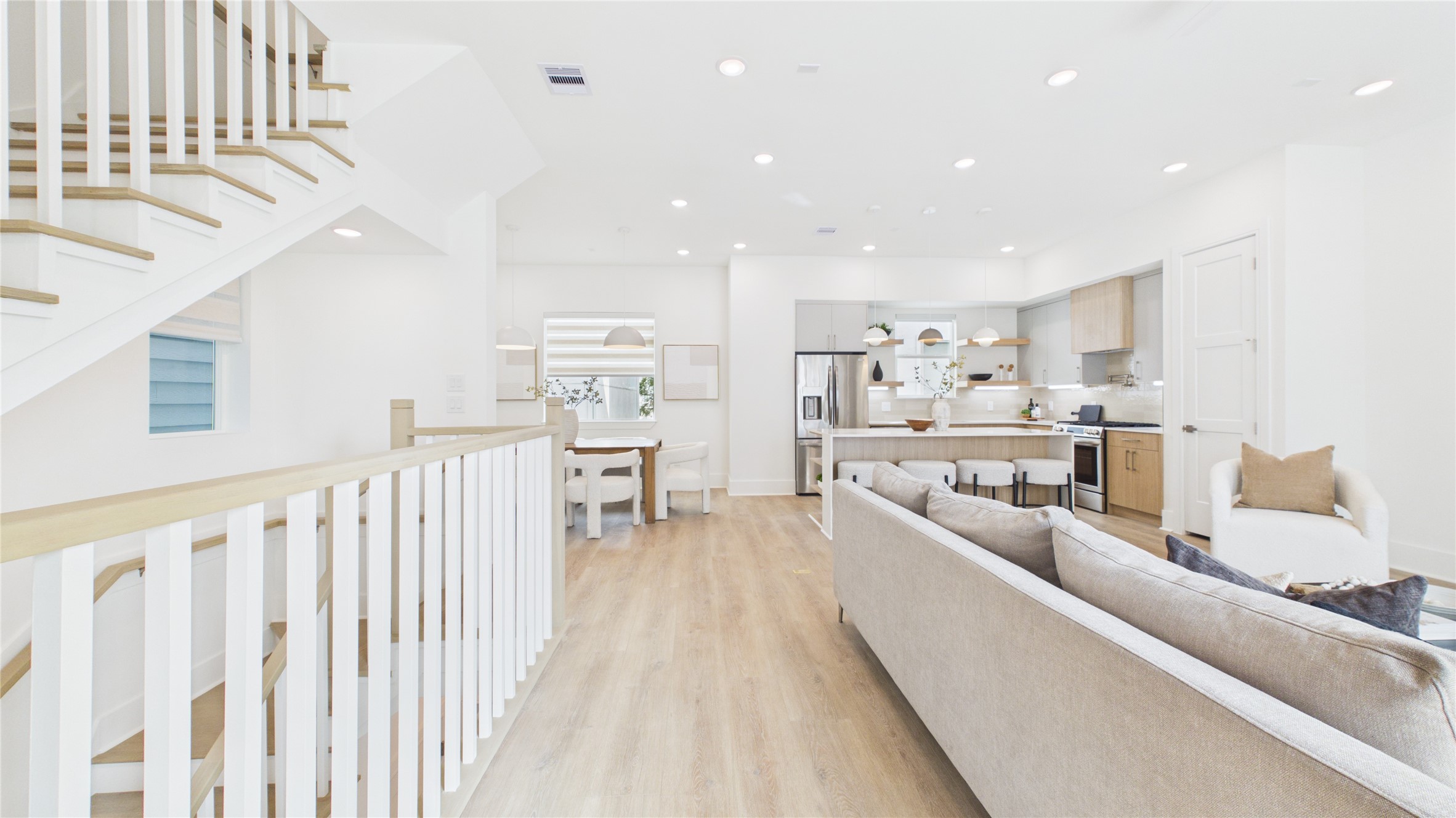 602 Skyland Terrace Way Houston, TX 77009 - Photo 15 of 40 This open-concept living space features a modern kitchen with stainless steel appliances, a cozy living area with a neutral color palette, and stylish wood flooring. The bright, airy atmosphere is enhanced by recessed lighting and a sleek staircase leading to the upper level.
