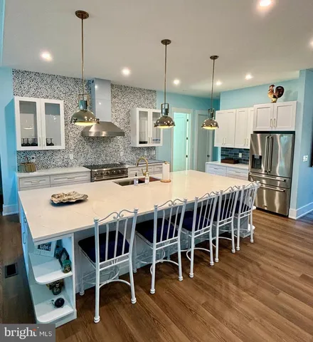 a kitchen with stainless steel appliances granite countertop a dining table chairs refrigerator and microwave