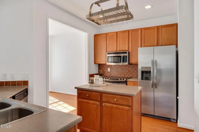 a kitchen with stainless steel appliances granite countertop a refrigerator a stove and a sink with wooden floor