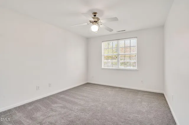 an empty room with a window and a ceiling fan