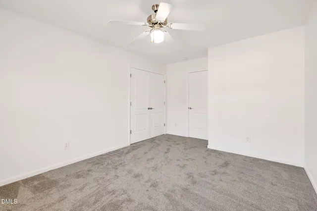 an empty room with a ceiling fan and a window