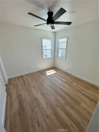 an empty room with windows and ceiling fan