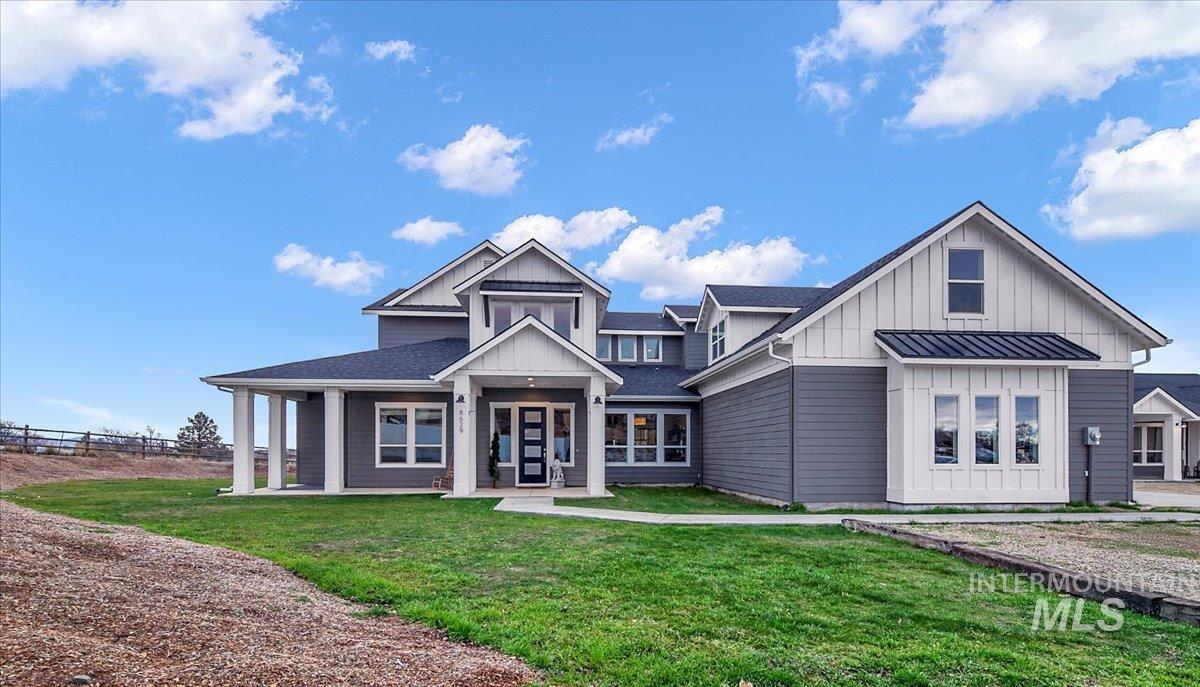 Modern inspired farmhouse with board and batten siding, a front yard, covered porch, and roof with shingles