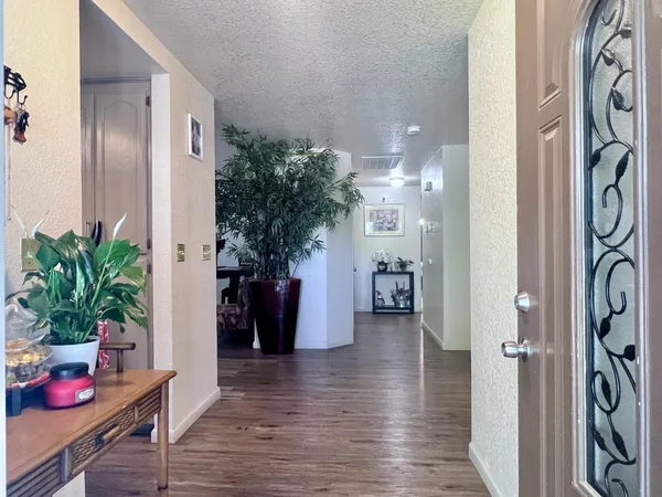 a hallway with wooden floor a table and a potted plant