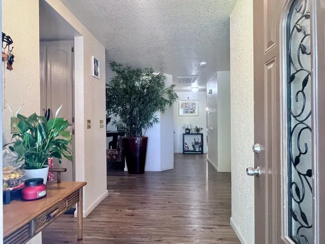 a hallway with wooden floor a table and a potted plant