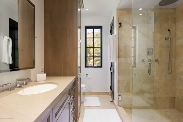 a bathroom with a granite countertop sink a mirror and shower