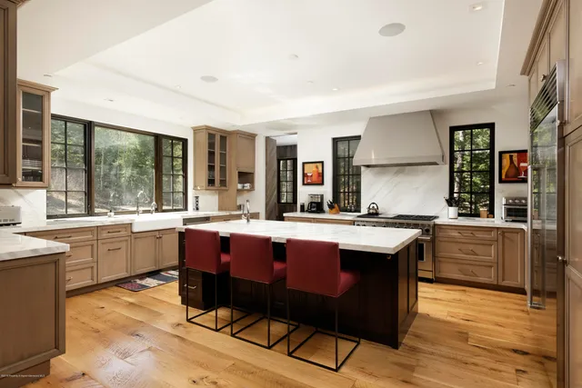 a large kitchen with a stove a sink dishwasher and a dining table with wooden floor