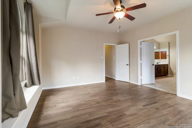 a view of a hallway with wooden floor and a ceiling fan